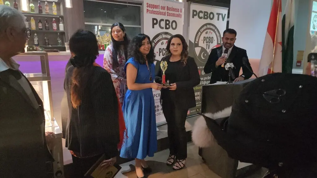 Guests holding their awards beside the PCBO banners