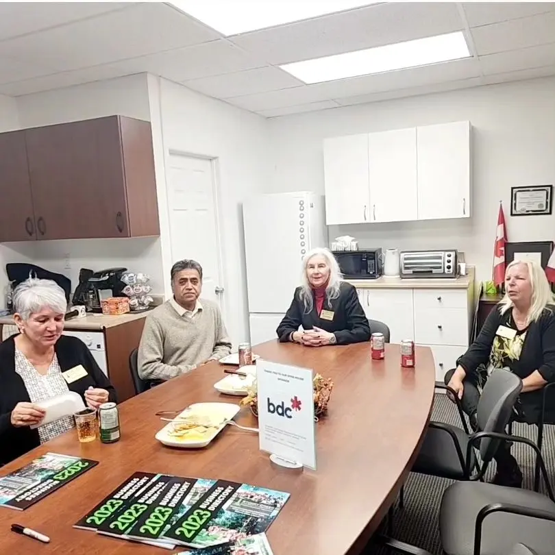 Chamber members around a meeting table with Small Business Week programs and a BDC sign