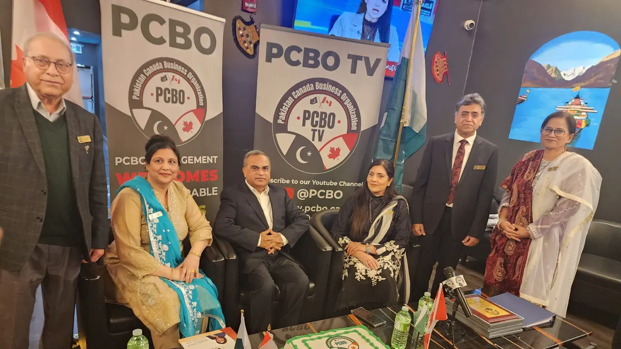 PCBO members, seated and standing, in front of the PCBO and PCBO TV banners