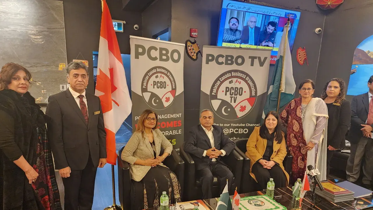 A larger group of members beside the Canadian flag and the PCBO TV banner