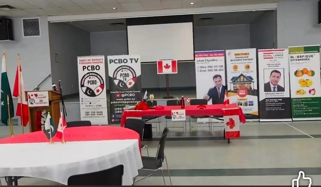 A Canada Day hall setup with red and white tables, a Canadian flag and PCBO and sponsor banners